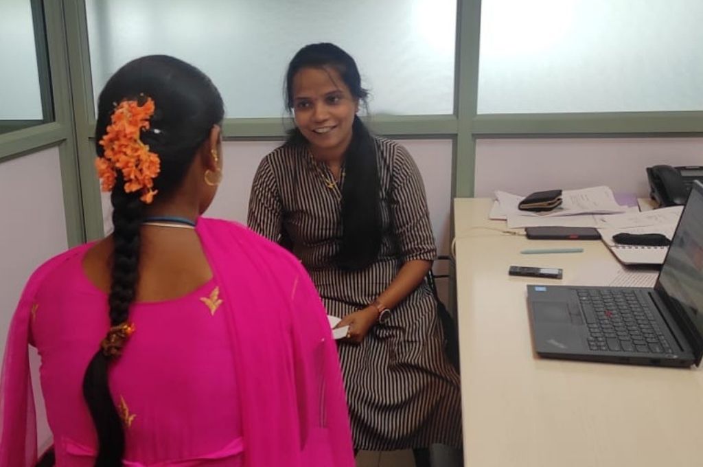 शैला, गुड बिजनेस लैब के साथ काम करने वाली एक गणनाकर टेबल पर बैठी हुई है जहां वह कपड़े के एक कारखाने में कर्मचारियों के साथ सर्वेक्षण का काम कर रही है-सर्वे कर्नाटक