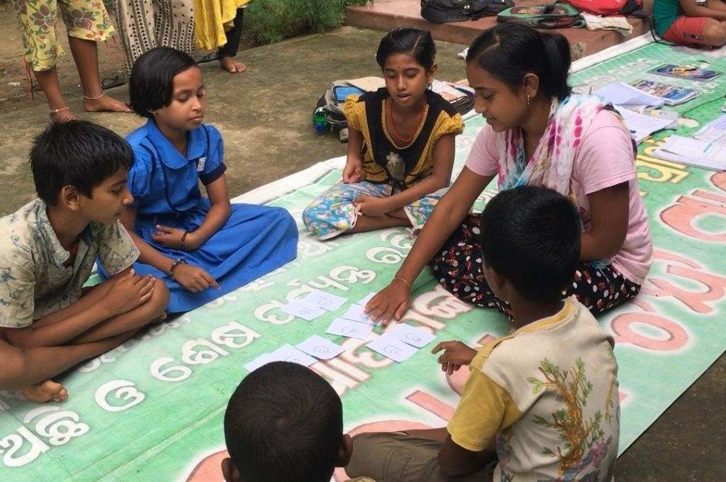 छात्रों से घिरे फर्श पर बैठे शिक्षक-ट्यूशन ओड़िशा