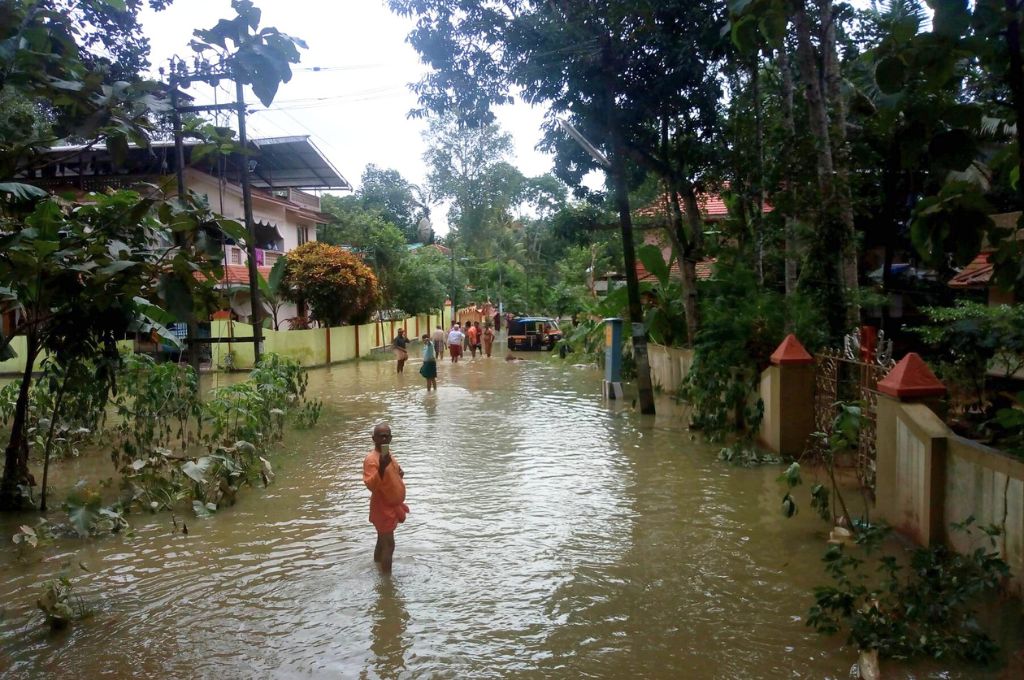 बाढ़ के पानी से भरी सड़क पर चलते लोग_आपदा प्रबंधन