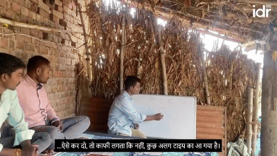 ग्रामीण परिवेश में लैपटॉप और व्हाइट बोर्ड पर गतिविधि कराते युवा पुरुष और महिला_समाँवेशी शिक्षा