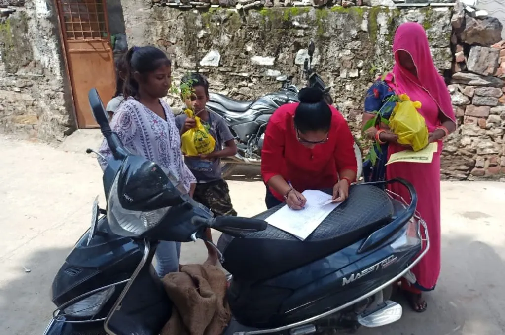 स्कूटी की सीट पर रखकर पेपर में कुछ लिखती महिला_महिला वन रक्षक