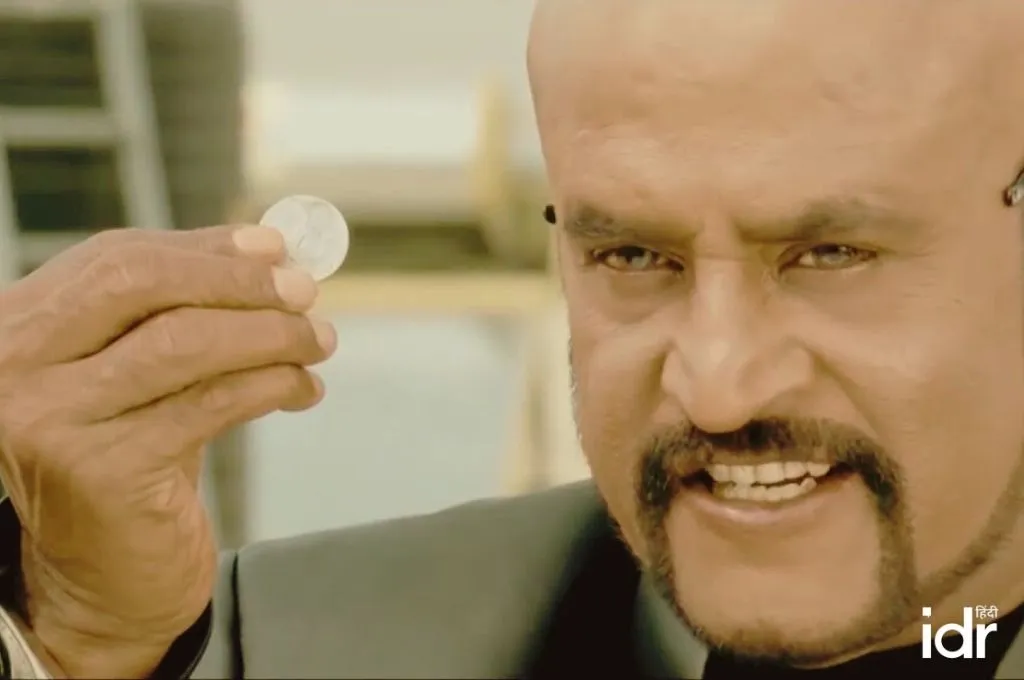 गंभीर भाव में सिक्का पकड़े अभिनेता रजनीकांत_पहेलियां