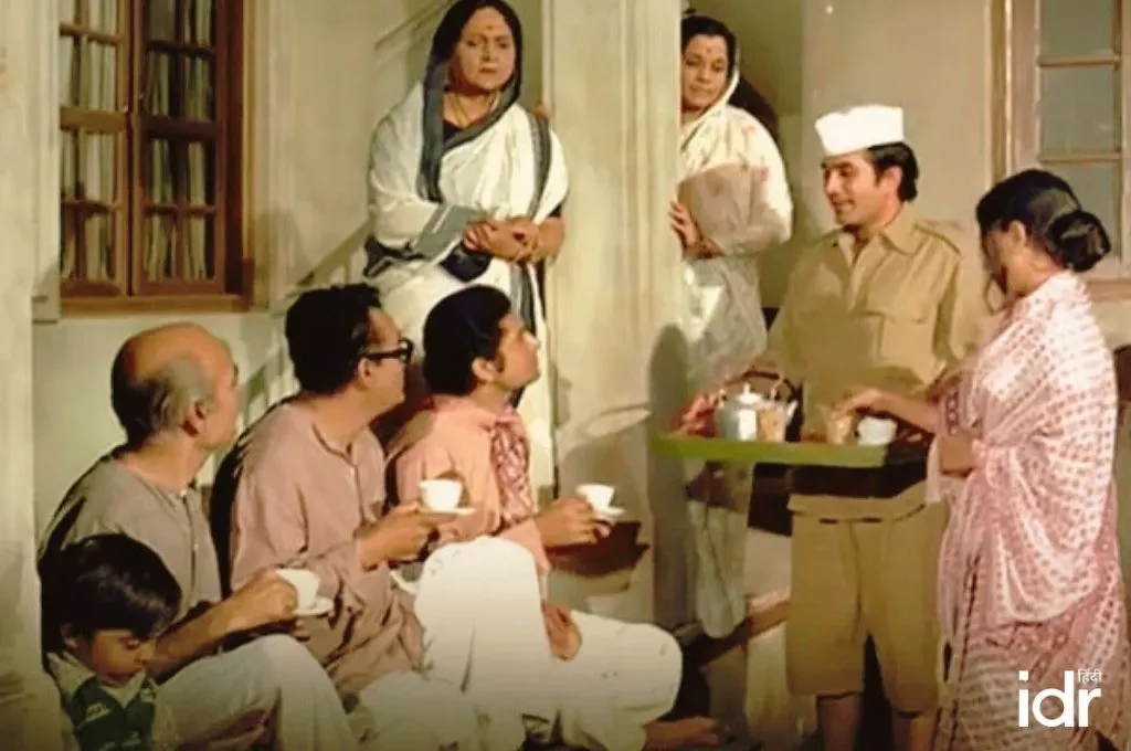 फिल्म के एक दृश्य में बरामदे में बैठे लोग चाय पीते हुए आपस में बातचीत कर रहे हैं, एक व्यक्ति ट्रे में चाय परोस रहा है।_पहेलियां