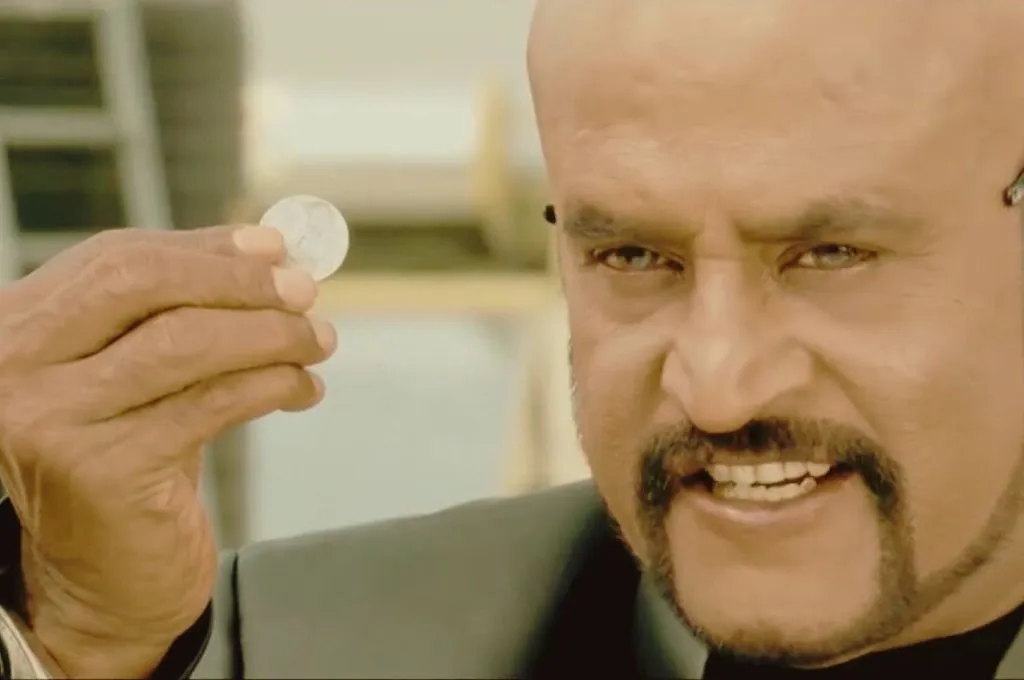 गंभीर भाव में सिक्का पकड़े अभिनेता रजनीकांत_पहेलियां