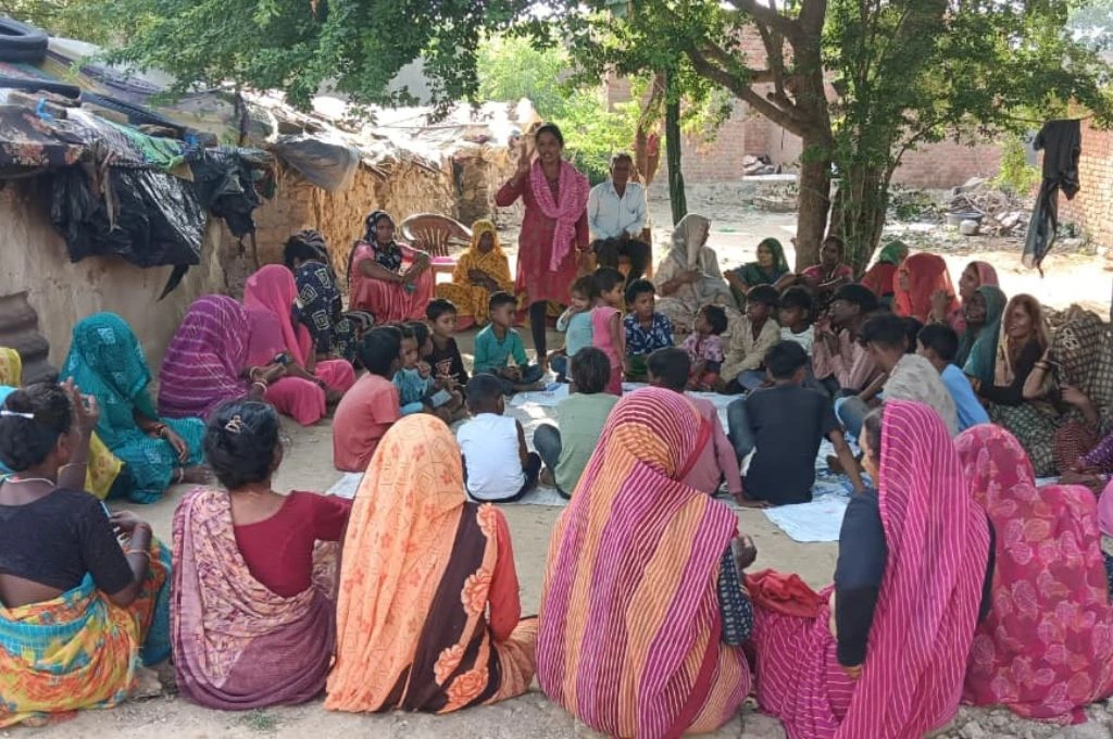 एक ग्राम सभा की बैठक का दृश्य, जिसमें एक महिला खड़े होकर बाकी लोगों से बात कर रही है_सहरिया