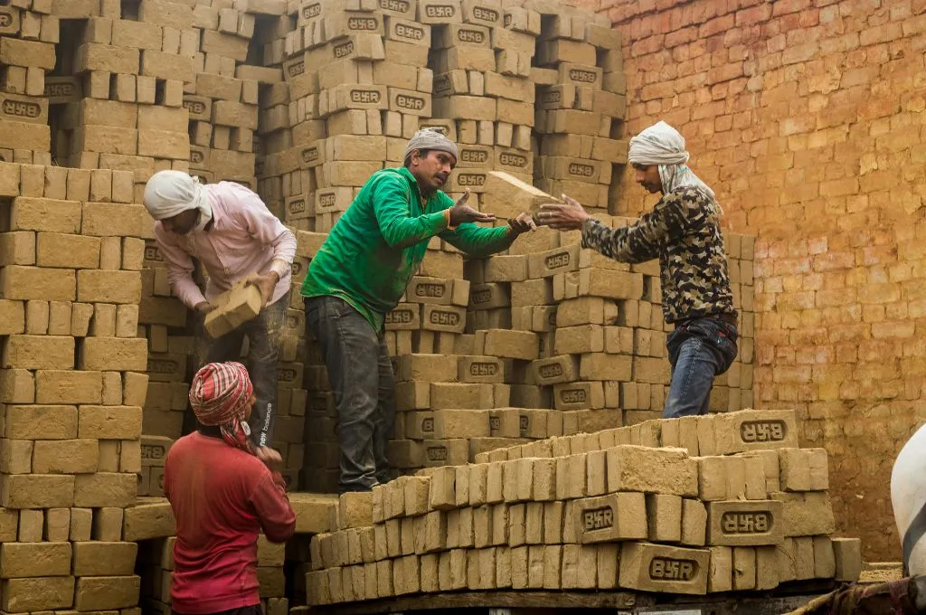 मिट्टी की ईंटों को लगाते हुए चार श्रमिक_युवा श्रम बल