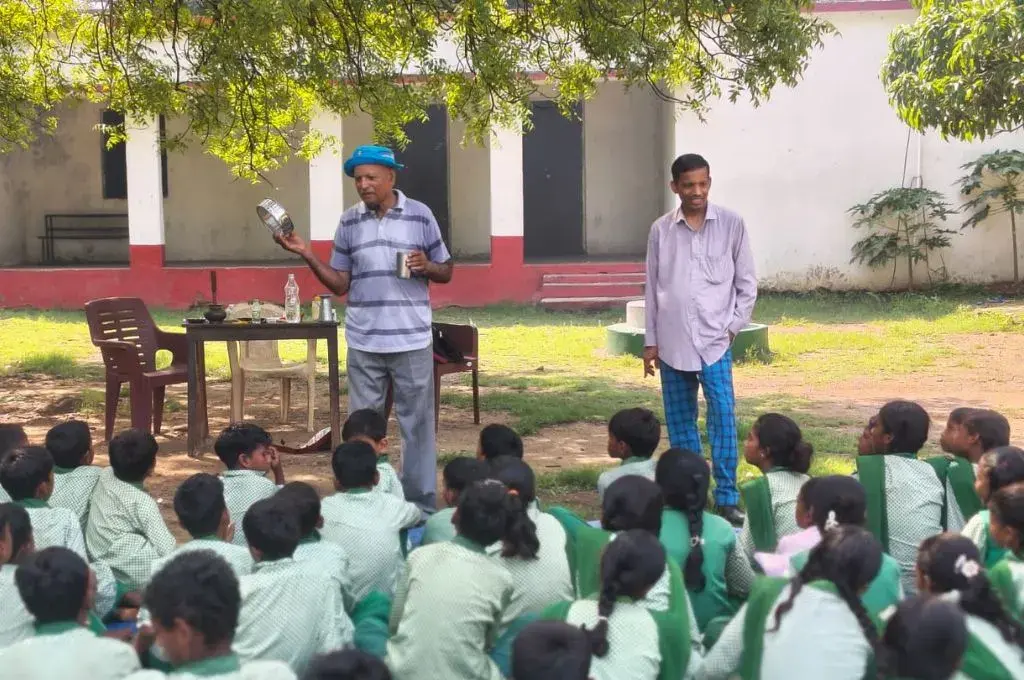 एक व्यक्ति स्कूली छात्रों की सभा को संबोधित करते हुए_अंधविश्वास