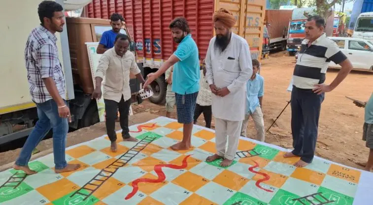सांप-सीढी का खेल खेलते लोग_ट्रक