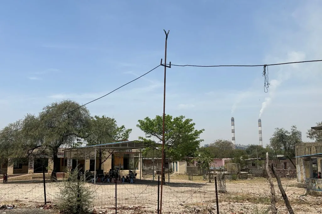किसी विद्यालय की इमारत के बाहर बैठकर पढ़ाई करते कुछ बच्चे और एक शिक्षक_छबड़ा थर्मल पावर प्लांट