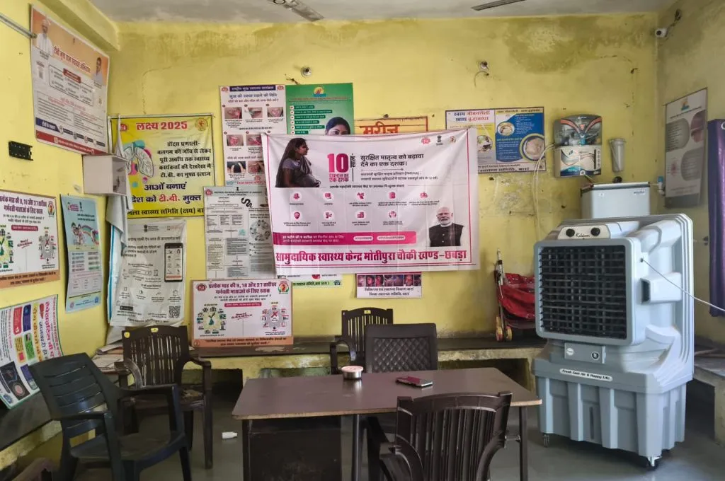 सरकारी अस्पताल के एक कमरे में दीवार पर टंगे कुछ बैनर, एक कूलर, एक मेज़ और कुछेक कुर्सियां_छबड़ा थर्मल पावर प्लांट