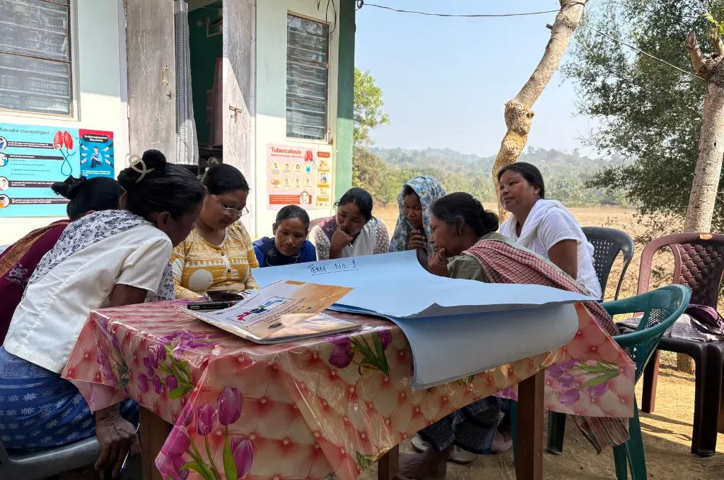 एक बड़े से चार्ट पेपर के साथ घेरे में बैठी कुछ महिलाएं_स्वास्थ्य नीति