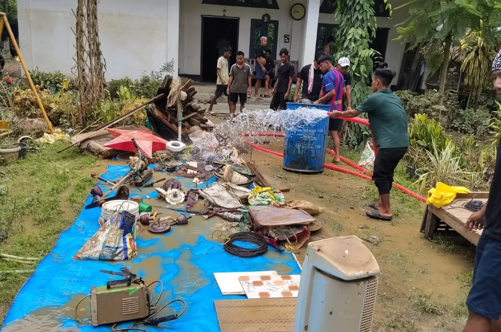 बाढ़ के बाद कीचड़ में सनी चीजों की पानी से सफ़ाई करते लोग_बाढ़