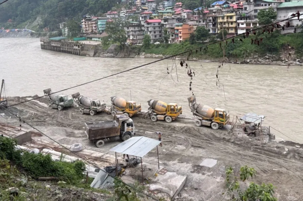 बहती नदी और उसके किनारे खड़ी कुछ मशीनें_नदियां
