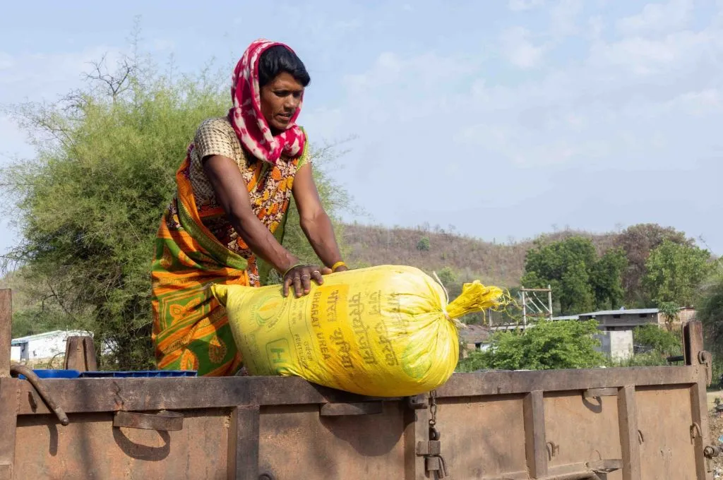 अनाज की बोरी के साथ एक महिला किसान_खेतीबाड़ी